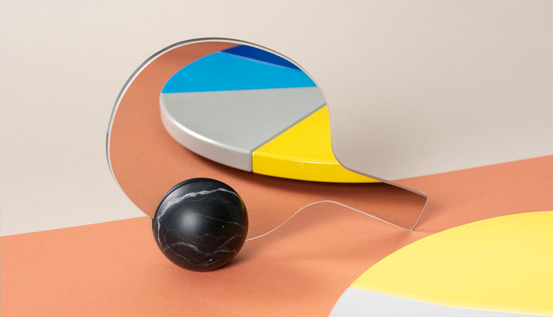 Un'interpretazione ironica dell'idea di sfidare l'immagine riflessa nello specchio, lo specchio da tavolo bifacciale Match ha la forma di una racchetta da ping pong poggiata su una sfera di marmo nero